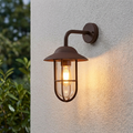 Rust brown nautical-style outdoor wall lantern with clear glass and a warm glowing bulb on a textured white wall.