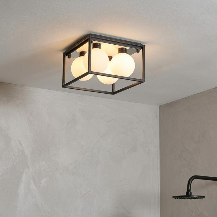 Square black metal frame bathroom ceiling light with four frosted globe bulbs in a modern interior.