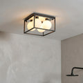 Square black metal frame bathroom ceiling light with four frosted globe bulbs in a modern interior.