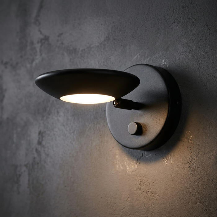 Trento Black Chrome Wall Light with an adjustable disk head and integrated dimmer on a textured grey wall.