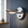 Chrome Trento wall light with adjustable disc head and integrated dimmer switch mounted on blue textured wallpaper.
