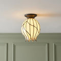 Tulip-shaped Tiffany flush ceiling light with cream glass panels and bronze mount against a green paneled wall.