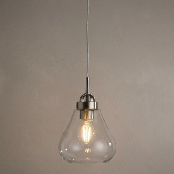 Antique chrome pendant light with a clear teardrop glass shade and glowing filament bulb.
