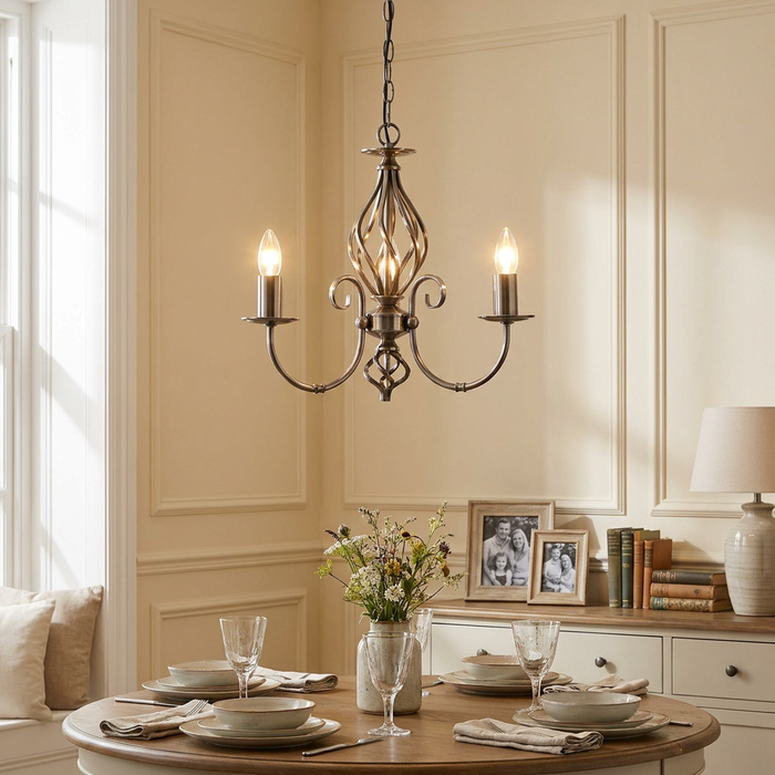 Tuscany Antique Silver 3 light chandelier hanging above a set dining table in a neutral room with paneled walls.