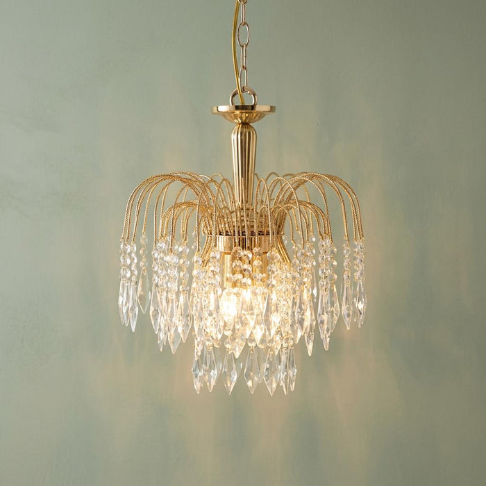 Gold 3 light waterfall ceiling pendant with cascading clear crystals against a textured green wall.