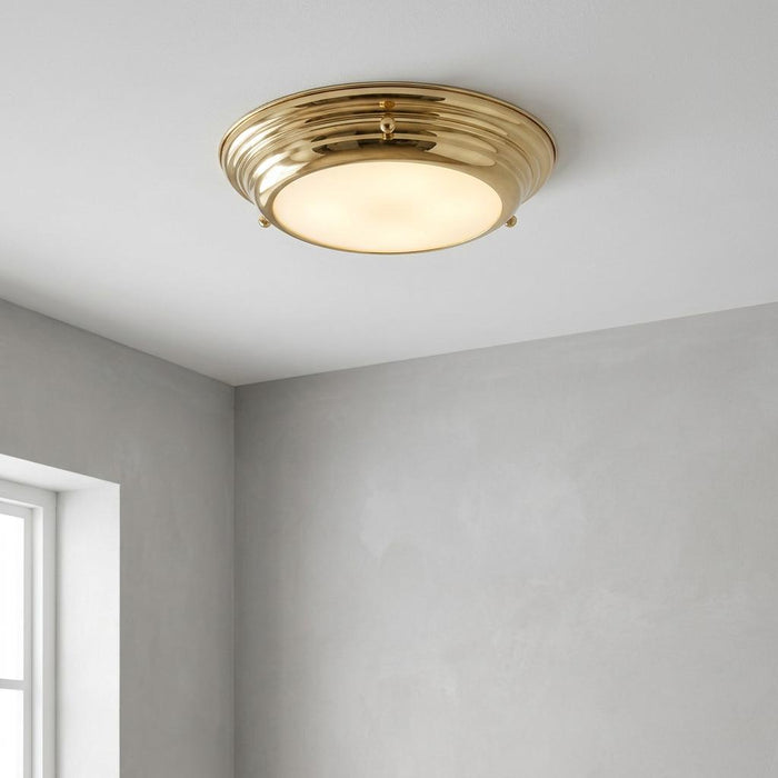 Polished brass mini LED flush bathroom ceiling light with frosted diffuser on a white ceiling.