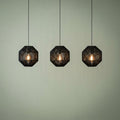 Three black rope effect pendant lights with glowing bulbs against a light green wall.