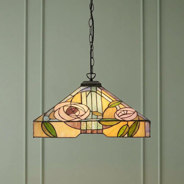 Stained glass Tiffany pendant light with a pink rose design hanging against a pale green paneled wall.