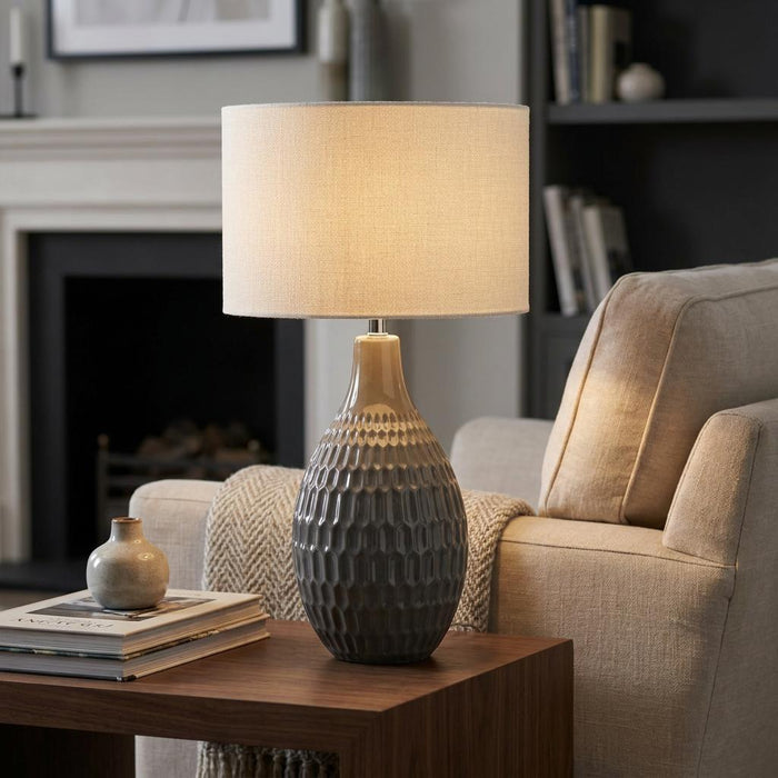 Yarra Grey Ceramic Table Lamp with a textured dimpled base and cream drum shade on a wooden side table.