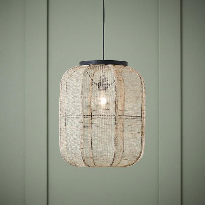 Zaire Natural Linen Adjustable Ceiling Pendant with a woven lantern shade hanging against a green paneled wall.